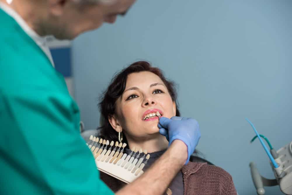 Dentist showing veneer shade options to patient during cosmetic consultation in North Sydney